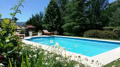 a swimming pool in a garden with flowers at Lomas del Vergel in Los Reartes