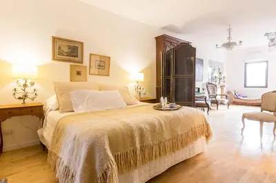 a bedroom with a large bed and a chair at Virreinato Hotel Boutique in Cordoba