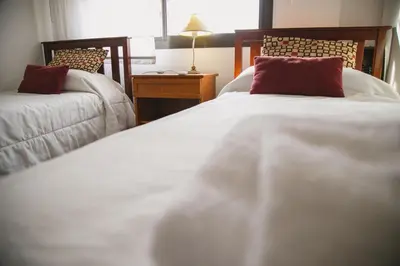 a bedroom with two beds with white sheets and red pillows at 4 PERSONAS A 150 Mts SANATORIO ALLENDE in Cordoba