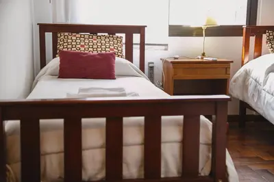 a bedroom with a bed with a red pillow and a night stand at 4 PERSONAS A 150 Mts SANATORIO ALLENDE in Cordoba