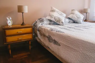 a bed with two pillows and a night stand with a lamp at 4 PERSONAS A 150 Mts SANATORIO ALLENDE in Cordoba
