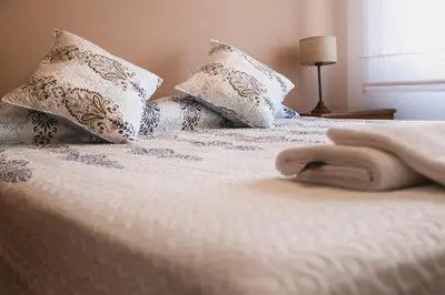 a bed with blue and white pillows on it at 4 PERSONAS A 150 Mts SANATORIO ALLENDE in Cordoba