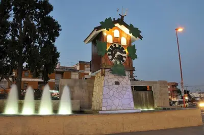 a clock tower in front of a building with a fountain at Departamento Centrico in Villa Carlos Paz