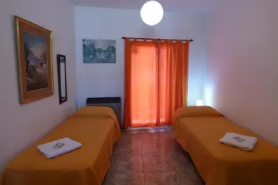 two beds in a hotel room with orange curtains at Departamento Centrico in Villa Carlos Paz