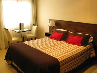 a bedroom with a large bed with two red pillows at Don Gregorio Spa in Merlo