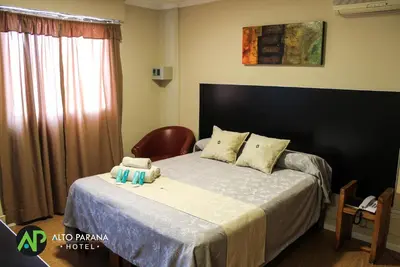 a bedroom with a bed with a chair and a window at Hotel Alto Parana in Cordoba
