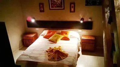 a bedroom with a bed with yellow and orange pillows at Cabañas el Recodo de Potrero in Potrero de Garay