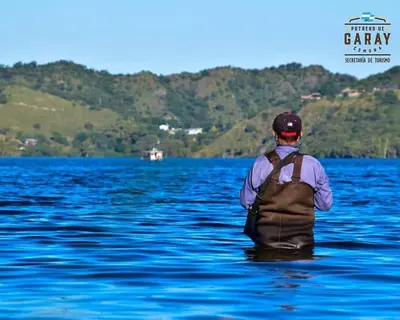 a man with a backpack sitting in the water at Cabañas el Recodo de Potrero in Potrero de Garay