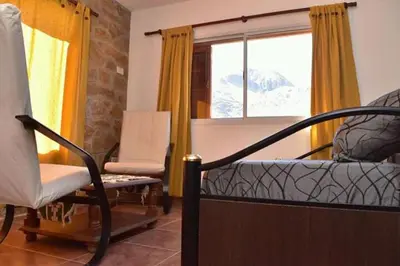 a living room with a bed and a chair and a window at Hostal 