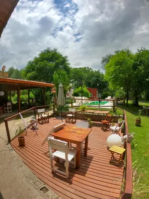 a wooden deck with a table and chairs and a pool at Posada Vieja Estancia in Santa Rosa de Calamuchita