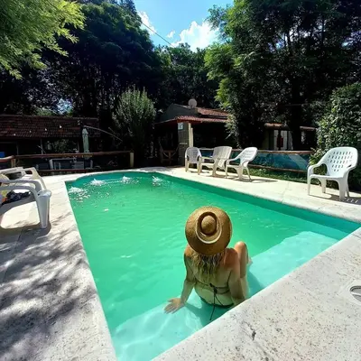 a woman in a straw hat sitting in a swimming pool at Posada Vieja Estancia in Santa Rosa de Calamuchita
