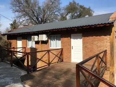 a brick house with a deck and a white door at Apart Don Cosme in Santa Rosa de Calamuchita