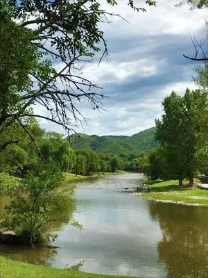 a river with trees and mountains in the background at Apart Don Cosme in Santa Rosa de Calamuchita