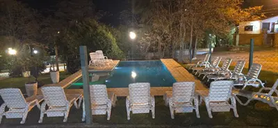 a group of chairs and tables next to a swimming pool at Belvedere Hotel para Adultos in Santa Rosa de Calamuchita