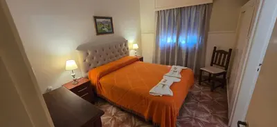 a bedroom with a bed with an orange blanket and a chair at Belvedere Hotel para Adultos in Santa Rosa de Calamuchita