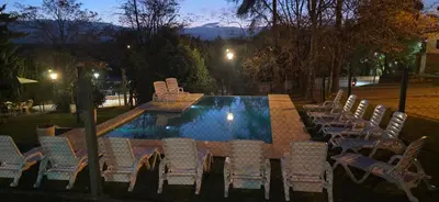 a table and chairs next to a swimming pool at Belvedere Hotel para Adultos in Santa Rosa de Calamuchita