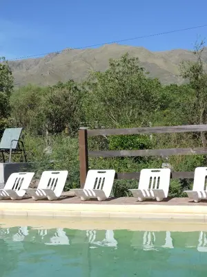 a row of lounge chairs next to a swimming pool at Cabañas La Comarca in Merlo