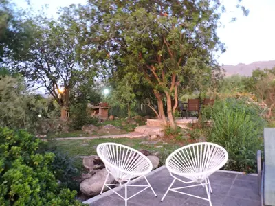 two white chairs sitting on a patio in a garden at Cabañas La Comarca in Merlo