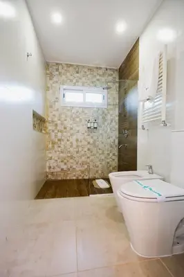 a white bathroom with a toilet and a shower at La Posada Del Qenti in Villa Carlos Paz