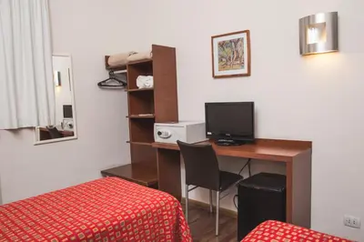 a room with a desk with a computer and a bed at Gran Hotel Victoria Cordoba Argentina in Cordoba