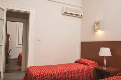 a hotel room with two beds and a red blanket at Gran Hotel Victoria Cordoba Argentina in Cordoba