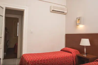 a hotel room with two beds and a red blanket at Gran Hotel Victoria Cordoba Argentina in Cordoba