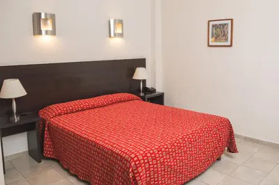 a bedroom with a red bed with two tables and two lamps at Gran Hotel Victoria Cordoba Argentina in Cordoba