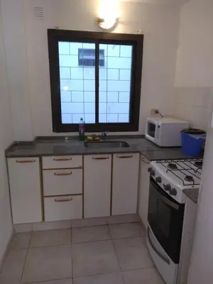 a kitchen with a sink and a stove and a window at Balcarce Suits PB in Bell Ville