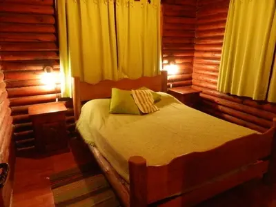 a bedroom with a bed in a log cabin at Las Cortaderas Cabañas de Tronco in Nono