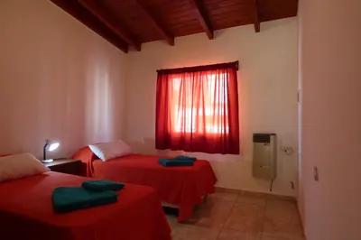 a room with two beds and a window with red sheets at Departamento Centrico Laprida in Cordoba