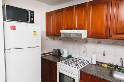 a kitchen with a white refrigerator and a stove top oven at 3 o 4 PERSONAS A 150 Mts SANATORIO ALLENDE in Cordoba