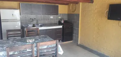 a kitchen with a table and a sink and a refrigerator at Inti Mayu in Villa Cura Brochero