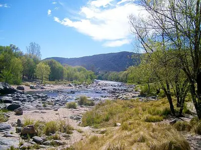 a river with rocks and trees in a field at San Antonio Querido in Villa Carlos Paz