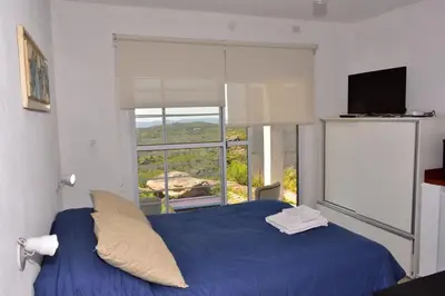 a bedroom with a blue bed with a large window at Departamento Pircas in Tanti