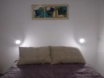 a bed with a pillow and a picture on the wall at Departamento Pircas in Tanti