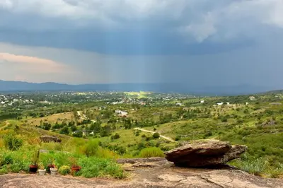a rock on a hill with a view of a city at Departamento Pircas in Tanti
