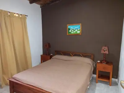 a bedroom with a bed and two night stands with lamps at Cabañas DAYMA in Trapiche