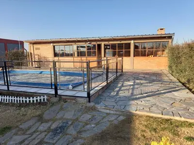 a house with a swimming pool in front of a building at Cabañas DAYMA in Trapiche