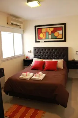a bedroom with a large bed with red pillows at Villa Cabrera Apart and Suites in Cordoba