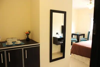 a bathroom with a mirror and a bed and a room at Villa Cabrera Apart and Suites in Cordoba