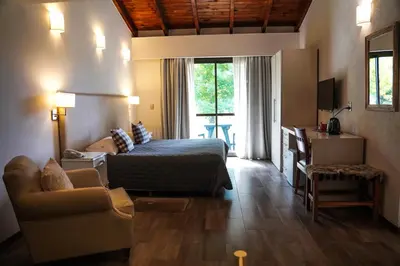 a bedroom with a bed and a living room with a couch at Posada Piedras Del Sol in Villa General Belgrano