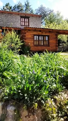 a log house with a garden in front of it at Cabañas 