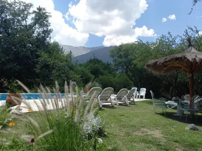a group of chairs and an umbrella next to a pool at Mainame Traslasierra in Los Hornillos