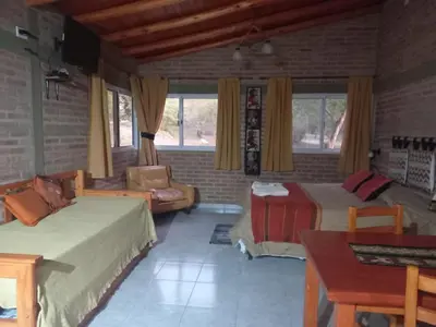 a bedroom with two beds and a couch and a table at Mainame Traslasierra in Los Hornillos