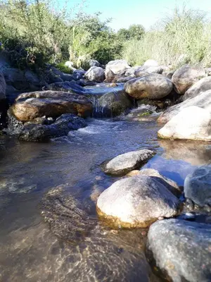 a stream of water with rocks in a river at Mainame Traslasierra in Los Hornillos