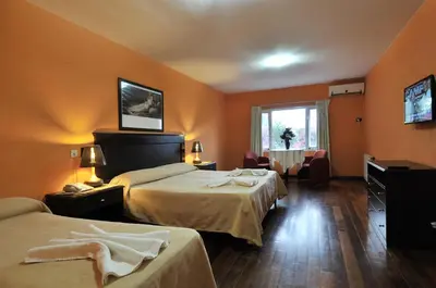a hotel room with two beds and a table at Hotel El Cid in Villa Carlos Paz