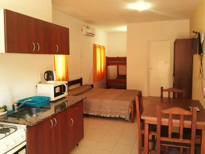 a kitchen and living room with a bed in a room at Departamentos Flor de Loto in Mina Clavero