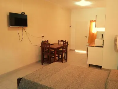 a room with a table and a kitchen with a refrigerator at Departamentos Flor de Loto in Mina Clavero