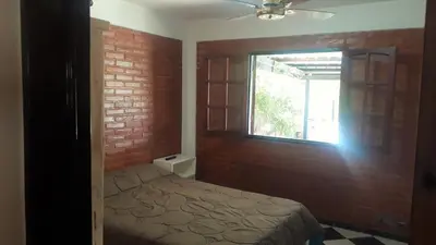 a bedroom with a bed with a brick wall and a window at Departamentos Flor de Loto in Mina Clavero