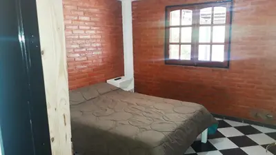 a small bedroom with a bed in a brick wall at Departamentos Flor de Loto in Mina Clavero